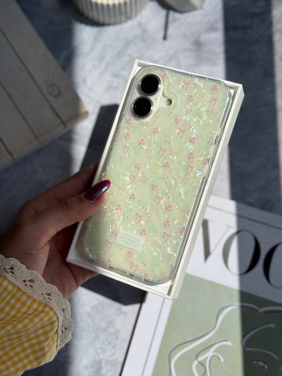 نمای نزدیک قاب آیفون یخی با طرح گلهای ریز صورتی و پاپیون ظریف